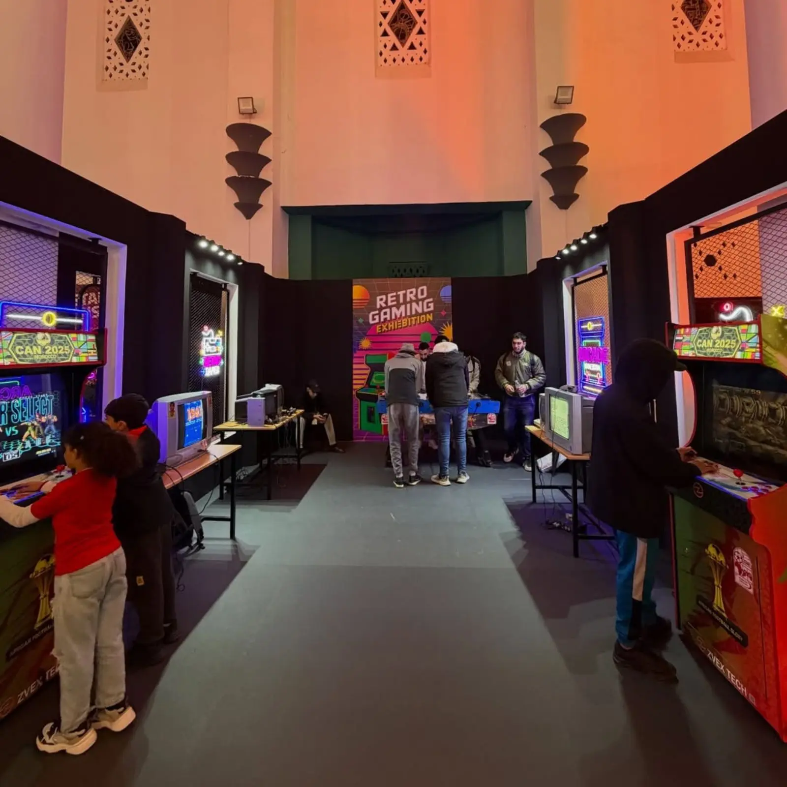 Espace Retro Gaming Exhibition aménagé dans la Fanzone Ezone à Casablanca pour la CAN 2025, avec bornes d’arcade rétro, consoles de jeux et animations gaming pour le public